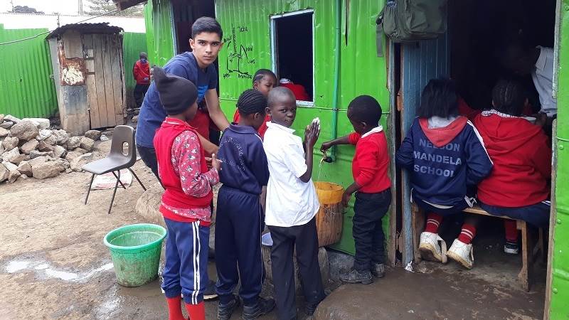 George, a Porridge and Rice volunteer from London, reminds children to wash their hands before meals