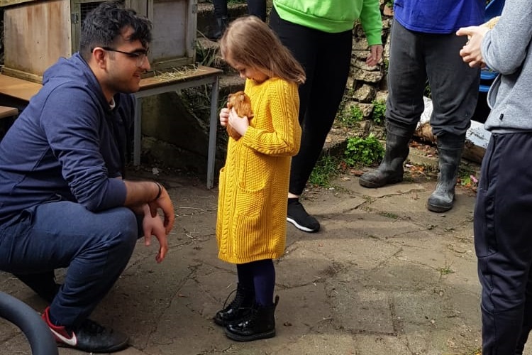 Mohit assist a young girl to hold a baby guinea pig at the petting day for Porridge and Rice